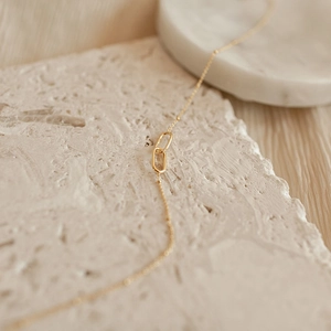 Macro shot of interlocking oval gold pendants on a satellite chain with a minimalist style