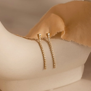 Gros plan de boucles d'oreilles à pompons dorés avec zircons sur socle céramique