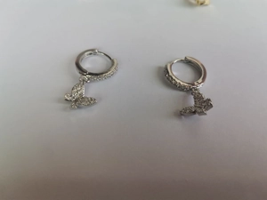 Close-up of silver butterfly hoop earrings featuring intricate zircon micro-pave detailing