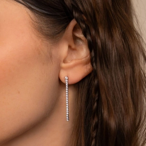 Gros plan d'une boucle d'oreille longue à pompon avec zircons sur une femme