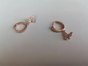 Macro detail of rose gold butterfly earrings with micro-inlaid cubic zirconia crystals