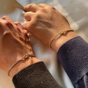 Close-up of gold and silver knot bangles on silk background for a luxury look