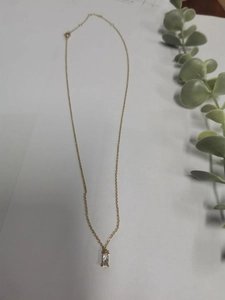 Detail of minimalist gold chain necklace featuring a square cubic zirconia pendant