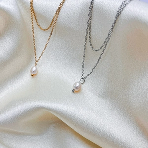 Détail de colliers doubles en or et argent avec d'élégantes perles blanches en poire