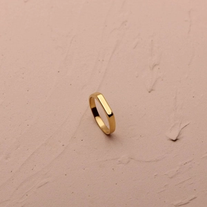 Macro shot of minimalist gold geometric ring with flat rectangular surface on stone