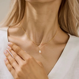Gros plan du collier double rang en acier doré avec pendentif perle élégant