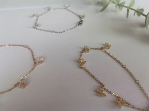 Détail de bracelets papillon élégants en or, or rose et argent avec pierres de zircon
