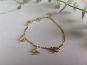 Vue détaillée d'un bracelet papillon doré orné de cinq pendentifs étincelants en zircone