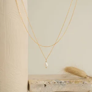Vue artistique d'un collier double rang en or avec perle sur un décor en pierre