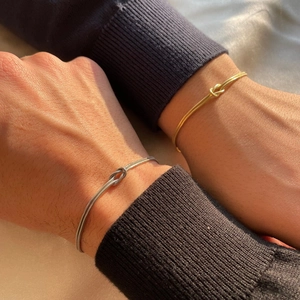 Detailed view of intertwined gold and silver snake bone bracelets with elegant knot design