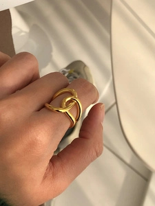 Close-up of artistic gold wrap-around ring with polished multi-layered design on hand