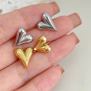 Détail de boucles d'oreilles en forme de cœur dorées et argentées à surface polie