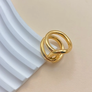 Detail of minimalist gold double interlaced rings on a white wavy geometric stand