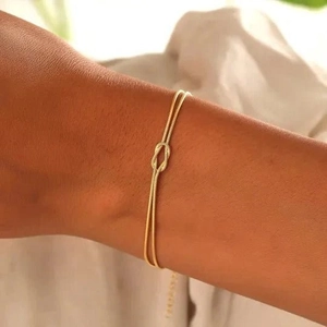 Close-up of elegant double gold snake chain bracelet with a central knot on wrist