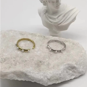Detailed view of adjustable gold and silver pearl rings on a natural stone base