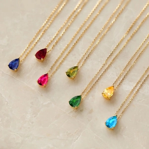 Détail de sept colliers dorés avec pendentifs en forme de goutte en pierre de naissance