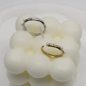 Detail of adjustable gold and silver rings with three white pearls on bubble candle