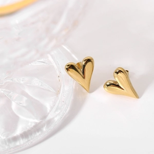 Vue macro de boucles d'oreilles cœur dorées avec finition polie sur fond blanc