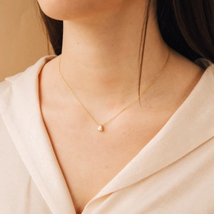 Gros plan d'un collier doré élégant avec zircone poire porté avec style au cou