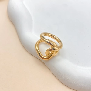 Macro shot of twisted gold stainless steel ring on a minimalist stone jewelry display