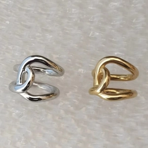 Close-up of minimalist gold and silver twisted ear cuffs in a polished metal finish
