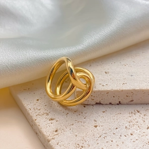 Detail of artistic gold overlapping multi-layer ring on a stone display with silk background