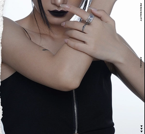 Close-up of layered silver rings with blue zircon and black square stone on a model