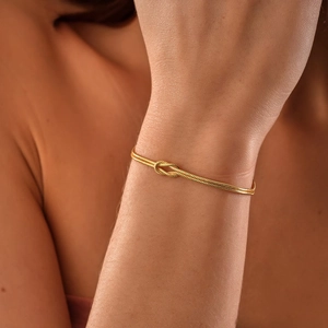 Detail of elegant gold double snake chain bracelet featuring a minimalist love knot