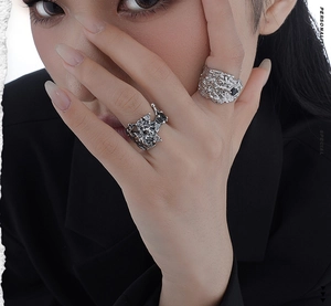 Detailed view of chunky S925 silver rings with lava texture and black gemstones on finger