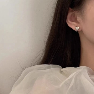 Boucles d'oreilles cœur en argent poli pour femme portées par un mannequin chic