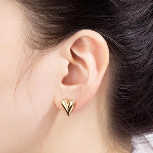 Boucles d'oreilles cœur en acier inoxydable doré brillant portées par un mannequin