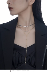 Détail du collier serpent argenté et collier en Y doré sur mannequin avec tenue noire