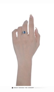 Detail of silver S925 ring with pear-cut blue gemstone and textured band on finger