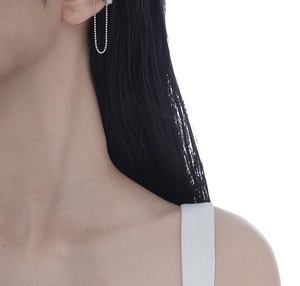 Gros plan d'un ear cuff en argent avec une chaîne délicate porté par un mannequin