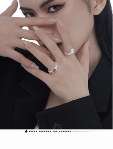 Detail of silver textured rings with pear-cut white and emerald-cut red gemstones