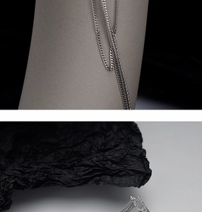 Macro view of polished silver asymmetric chain fringe earrings with textured surface
