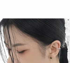 Detail of S925 silver earring chain with emerald gemstone and cuff on a model