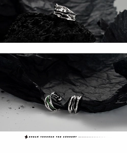 Detail of silver lava texture ear cuff with green enamel inlay on dark stone background