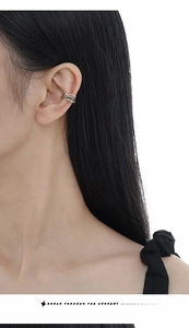 Detail of silver ear cuff with green enamel accent worn on ear by a model