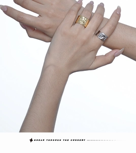 Detailed view of hammered gold and wrinkled silver wide bands on model hand