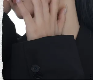 Detail of black blazer sleeve with four buttons and textured twill fabric detail