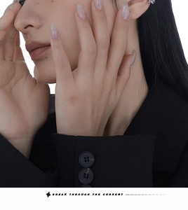 Close-up of minimalist silver zircon ear cuff worn by model in black blazer