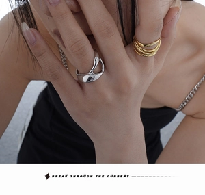 Irregular liquid silver ring and layered gold bands worn by a model in a fashion close-up