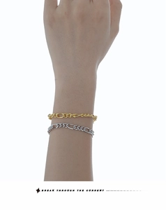 Détail de bracelets gourmettes Figaro argent et or portés sur fond blanc minimaliste