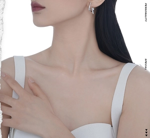 Close-up of asymmetrical twisted silver earrings worn by a model in minimalist style