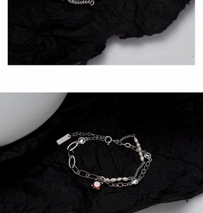 Close-up of S925 silver layered bracelet with red gemstone and baroque pearls detail