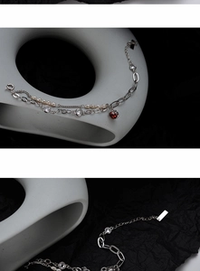 Close-up of double-layer silver bracelet with Baroque pearls and red gemstone charm