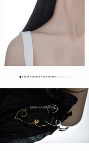 Detailed view of asymmetric twisted line earrings in gold and silver metal finishes