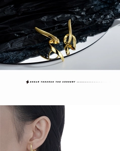 Macro shot of asymmetric gold-tone twisted wire earrings and model wearing the long studs