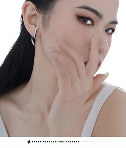 Close-up of asymmetrical S925 sterling silver wire earring worn by female model